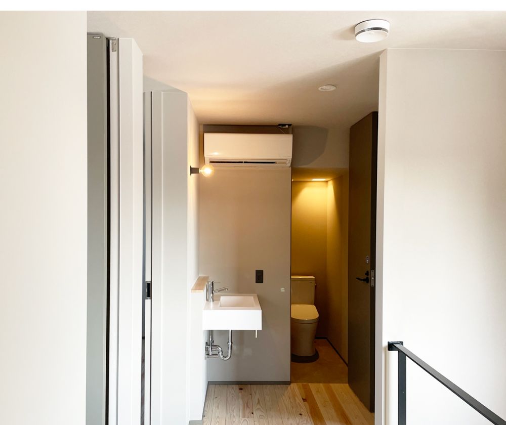 洗面台とトイレが並ぶシンプルで明るい室内の廊下